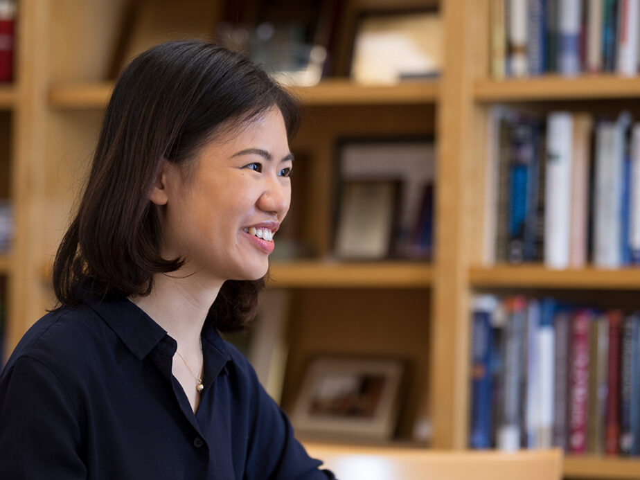 A woman wearing a blue button-up shirt smiles and look to her left out of frame